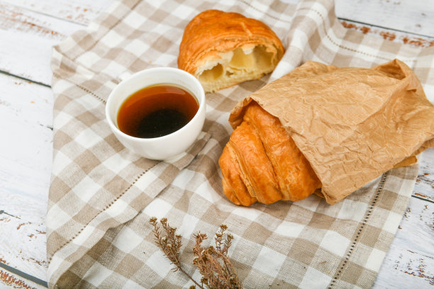 早餐,羊角面包。清晨的开始。新的法国羊角面包。木质背景上放着咖啡杯和新鲜烘焙的羊角面包。从以上观点。早餐有羊角面包和咖啡图片下载
