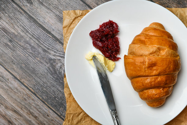 早餐,羊角面包。清晨的开始。新的法国羊角面包。木质背景上放着咖啡杯和新鲜烘焙的羊角面包。从以上观点。早餐有羊角面包和咖啡图片下载