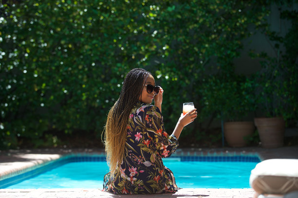 后视图放松在游泳池有一个果汁看着肩膀图片下载