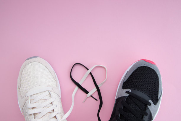 男性和女性白色和黑色的运动鞋和鞋带在粉红色的背景上的心的形式。他和她都很健康。体育爱好者。在家锻炼。本空间图片下载