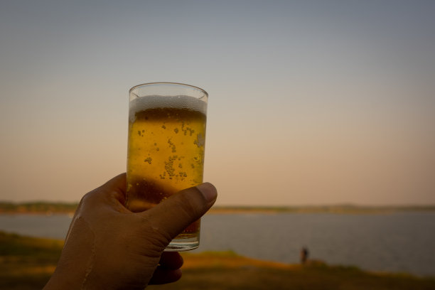 啤酒杯在蓝天和河流的背景上展示图片下载