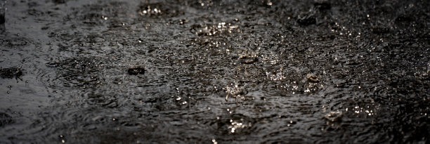 雨落在地面上，黑色的雨天气背景，水泡和水花在水面上，刷新自然上的水滴水模式，美丽的散水滴水图片下载