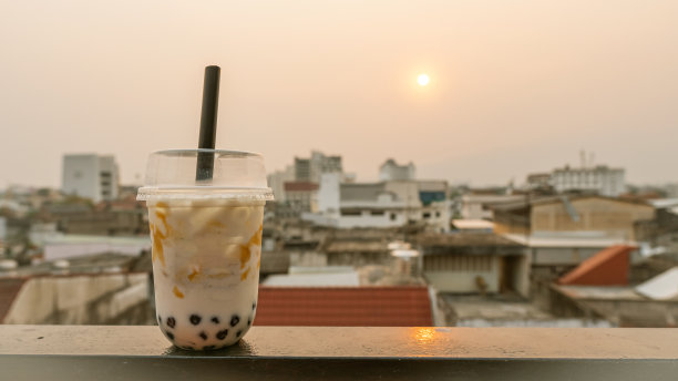 桌上的珍珠奶茶和冰茶，背景是建筑物和阳光素材图片