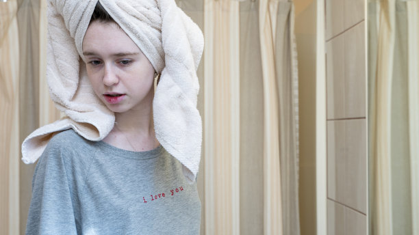 一个年轻女子在浴室里用浴巾盖住头发的肖像。图片下载