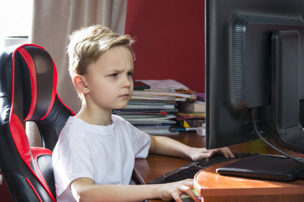 有趣的男孩在桌子上玩电脑图片下载