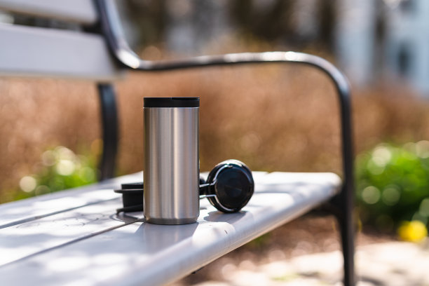 耳机和咖啡放在可重复使用的旅行杯里图片下载