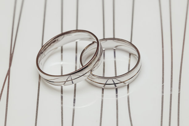 一对结婚戒指放在有银色线条的白色大理石表面上图片下载
