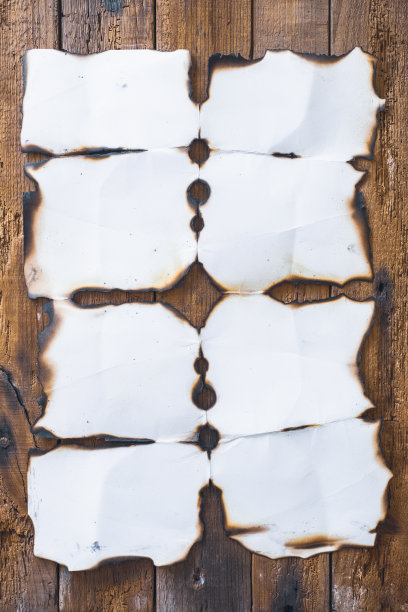 烧糊的纸在粗糙的木板上。图片下载