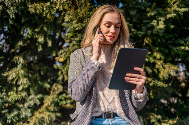 年轻女子使用手机和数码平板电脑户外库存照片图片下载