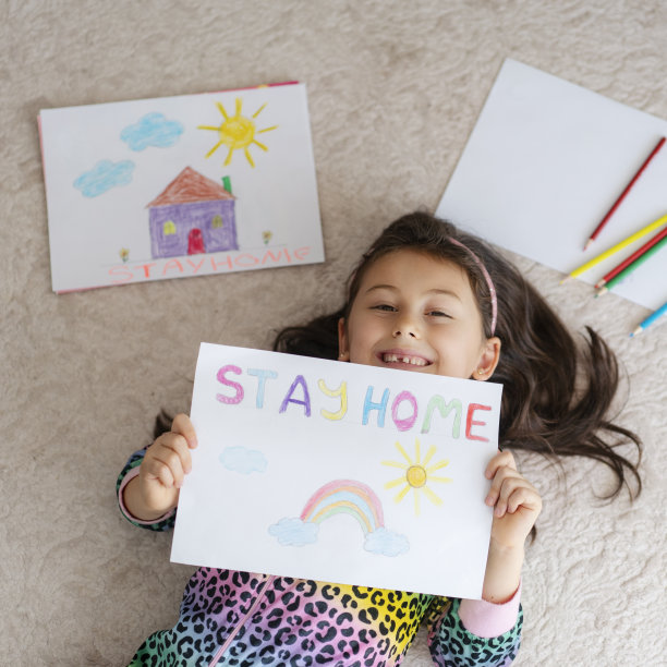可爱的小女孩在家画画，在纸上写着“呆在家里”的话图片下载