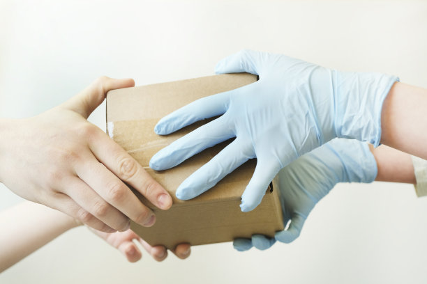 送货员拿着装着医用橡胶手套的纸箱。快速免费送货运输。副本的空间。网上购物和快递。特写镜头。白色背景图片下载