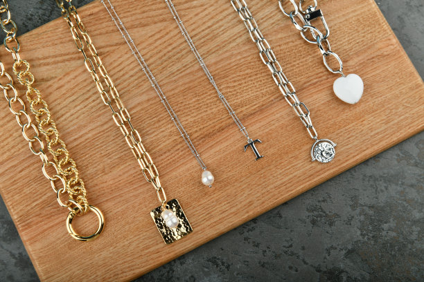 金银手工制作的链条。在木制的背景上。装饰链上的装饰品。适合手工制作和爱好的材料。彩色背景的银和金链图片下载