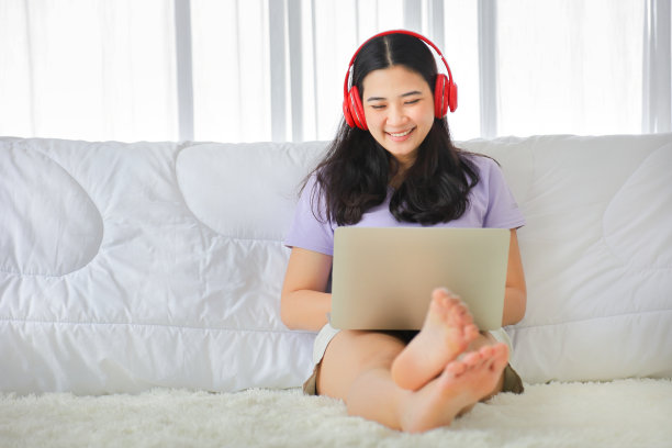 年轻漂亮的女孩看电影从家里在她的床上使用电脑笔记本电脑访问媒体在线图片下载