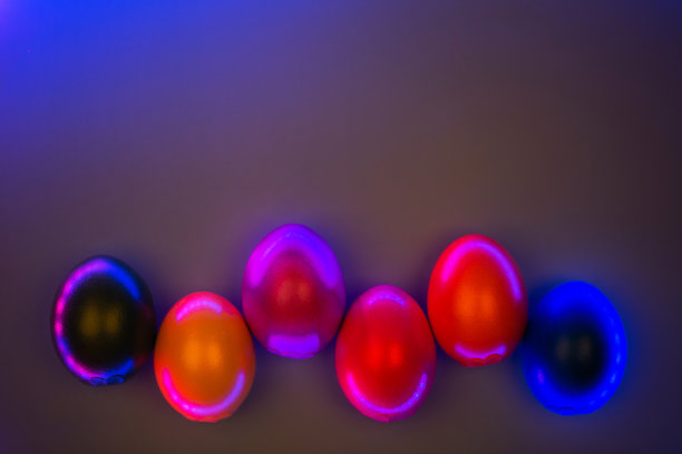 彩色鸡蛋的创意照片在霓虹灯在灰色的背景。图片下载
