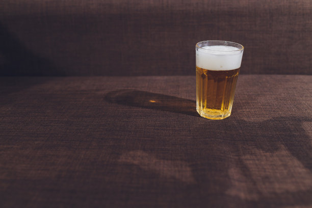 家庭酗酒。啤酒瓶和洒在沙发上的啤酒。图片下载