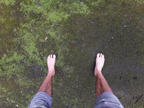 年轻人赤脚站在柔软的青苔上，感觉脚踏实地图片下载
