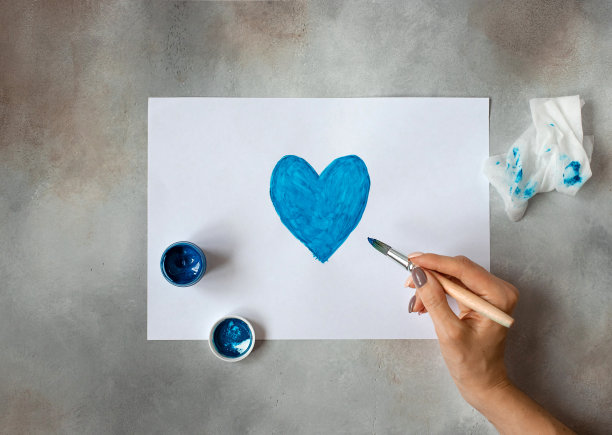女人画一幅画。用蓝色颜料画的心。图片下载