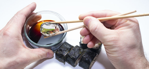 男子用筷子吃寿司卷。这是一个很简单的计划。日本厨房。全景照片图片下载