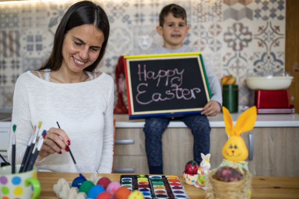 妈妈在画复活节彩蛋，而儿子正拿着一张快乐的复活节黑板照片图片下载