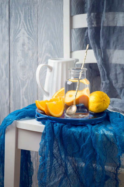 在乡村的背景上，椅子上有鲜橙和水的静物画图片下载