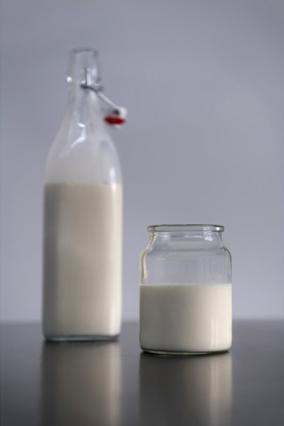 一个杯子和一个装满牛奶的瓶子，放在桌子上。图片下载