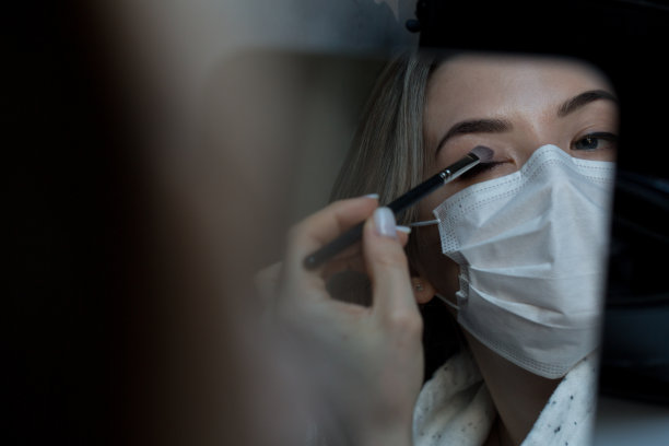 用防冠状病毒防护口罩化妆。新型冠状病毒肺炎Covid-20。年轻女性化妆。美容院图片下载