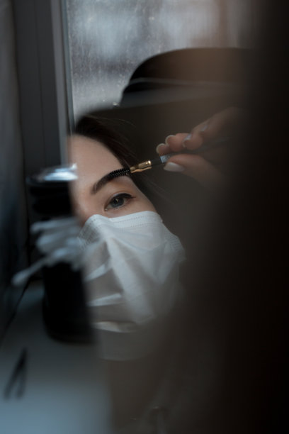 用防冠状病毒防护口罩化妆。新型冠状病毒肺炎Covid-20。年轻女性化妆。图片下载