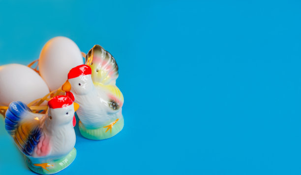美丽的复活节装饰，在蓝色背景的篮子里有一只公鸡，母鸡和鸡蛋。副本的空间。图片下载