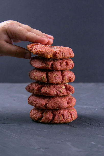 孩子的手伸向新鲜烤甜菜片燕麦饼干在一个砖块桌子的背景。节日庆典和烹饪概念。有选择性的重点图片下载