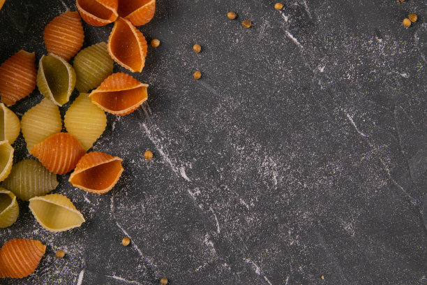 意大利面食Conchiglie Rigate，混合了五颜六色的生壳散落在桌子上，留下了一片空白。质感的意大利食物背景概念。俯视图平放近图片下载