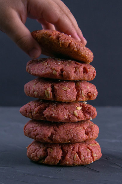 孩子的手伸向新鲜烤甜菜片燕麦饼干在一个砖块桌子的背景。节日庆典和烹饪概念。有选择性的重点图片下载
