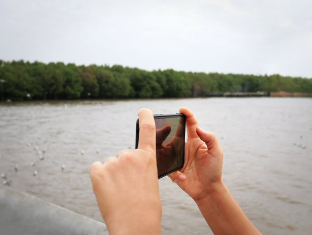 手拿手机拍摄海景图片下载