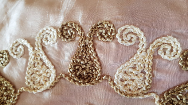 复古绣花图案桌布特写。在白色缎子表面上装饰着传统的米色和浅棕色装饰，具有华丽的纺织质感。图片下载