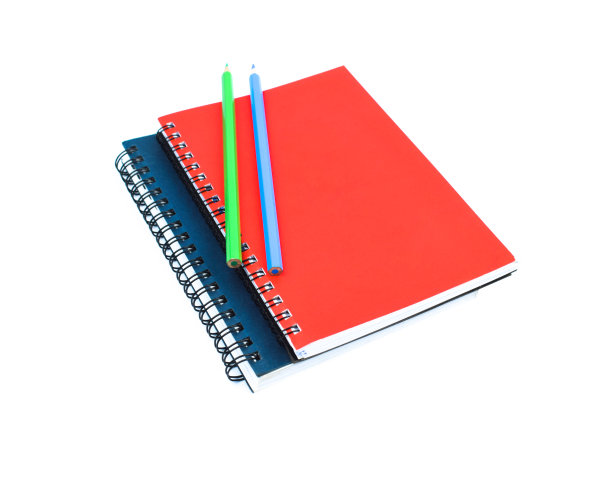 绿色和蓝色的木铅笔蜡笔放在两个不同颜色的日记上面，在白色的背景上图片下载