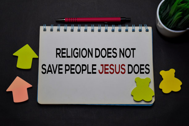 宗教不能拯救人们耶稣确实在一本孤立在办公桌上的书上写字。基督教信仰的概念图片下载
