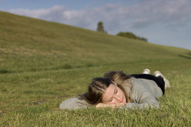 一个女孩放松地躺在草地上，闭着眼睛图片下载
