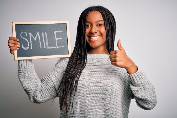 年轻的非洲裔美国妇女拿着黑板与微笑的单词文本在孤立的背景高兴与大微笑做ok的手势，拇指向上的手指，优秀的手势图片下载