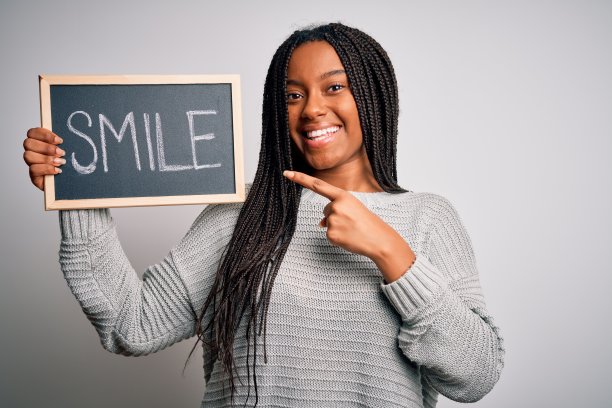 年轻的非洲裔美国妇女在孤立的背景下非常高兴地用手和手指指着黑板与微笑的文字图片下载