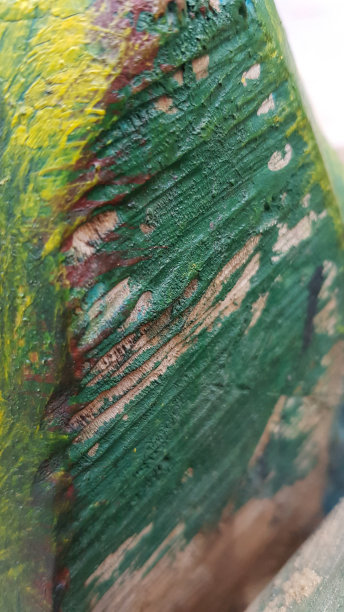 手工雕刻的木纹表面，涂上绿色和黄色的油漆。柔软的焦点，以肋木纹理。木工行业背景摘要。图片下载