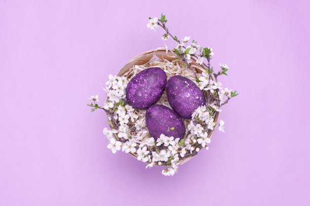 紫罗兰色的复活节彩蛋装在篮子里，花在紫罗兰色的背景上。水平的照片。俯视图图片下载