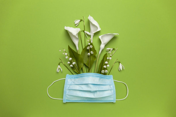 春天的花朵与医疗面具在绿色的背景。过敏与冠状病毒(2019-ncov, covid 2019)大流行。雪花莲，铃兰和马蹄莲图片下载