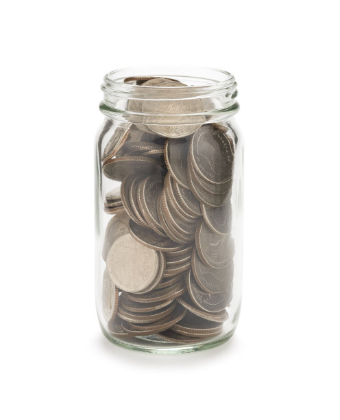 在白色背景的玻璃罐子里装满硬币的特写。孤立与剪辑路径照片和节省投资的概念。图片下载