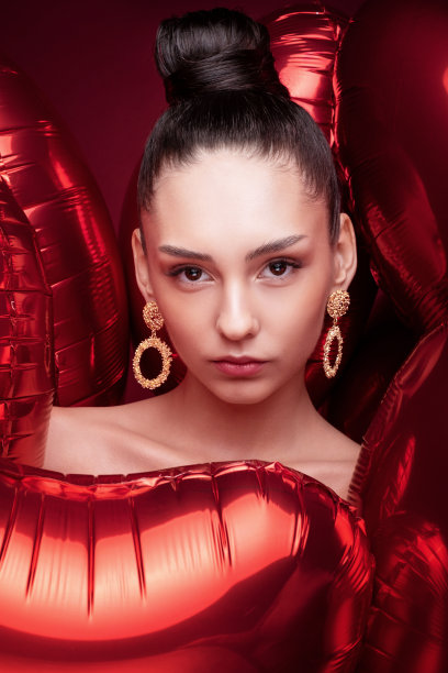 特写美女肖像时尚模特在气球，干净的皮肤，红色的背景，金色耳环，发型高发髻，艺术创意时尚摄影，图片下载