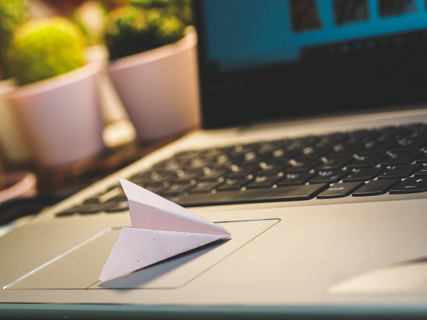 用笔记本电脑工作的地方有纸飞机。图片下载