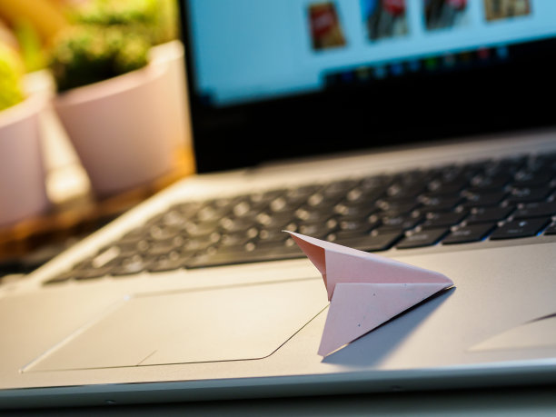 用笔记本电脑工作的地方有纸飞机。图片下载