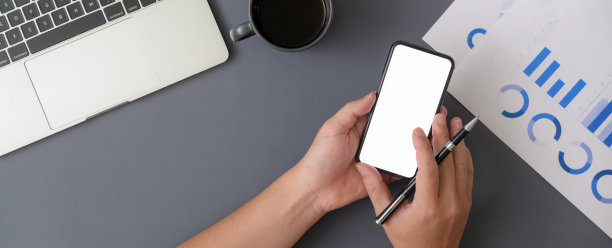 头顶拍摄的商人使用模拟智能手机，同时使用笔记本电脑和文书工作图片下载