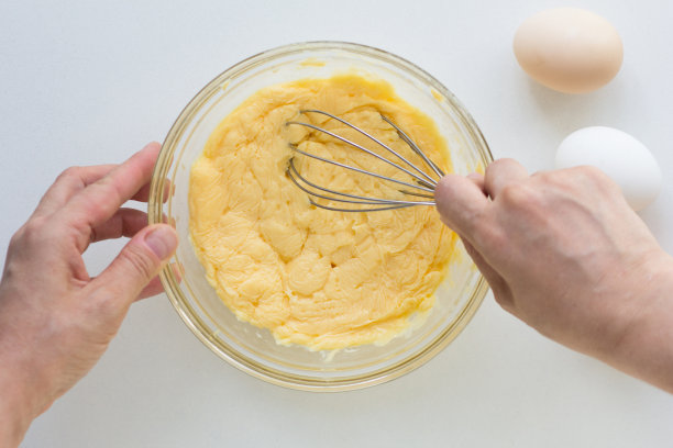 女子手拿搅拌器在白色背景上打蛋奶酱的俯视图图片下载