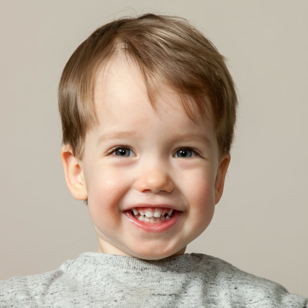 一个2岁男婴在米色背景的工作室肖像图片下载