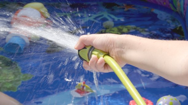 从花园里的水管中向充气池注水图片下载