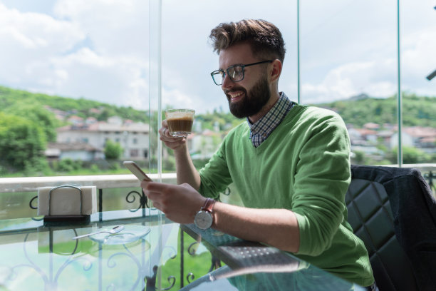 年轻人在阳光明媚的阳台上喝咖啡图片下载